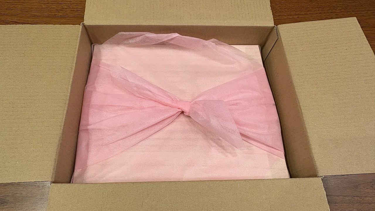 ジャパネットおせちはピンクの風呂敷に包まれた状態で段ボールに入っている。